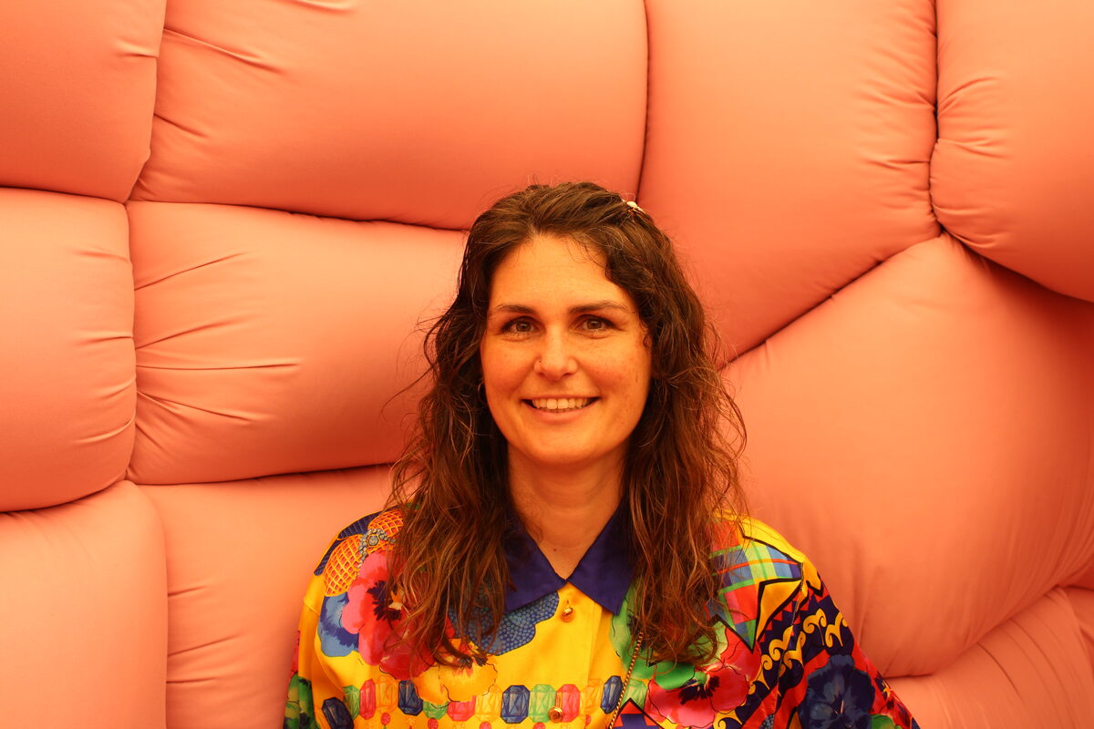Gabriëlle in a colored blouse in front of orange artwork