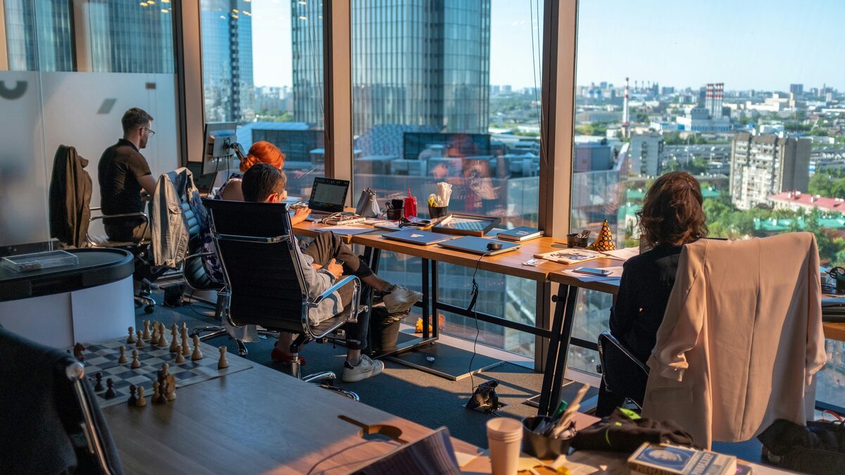 People working on laptops in an office overlooking the city
